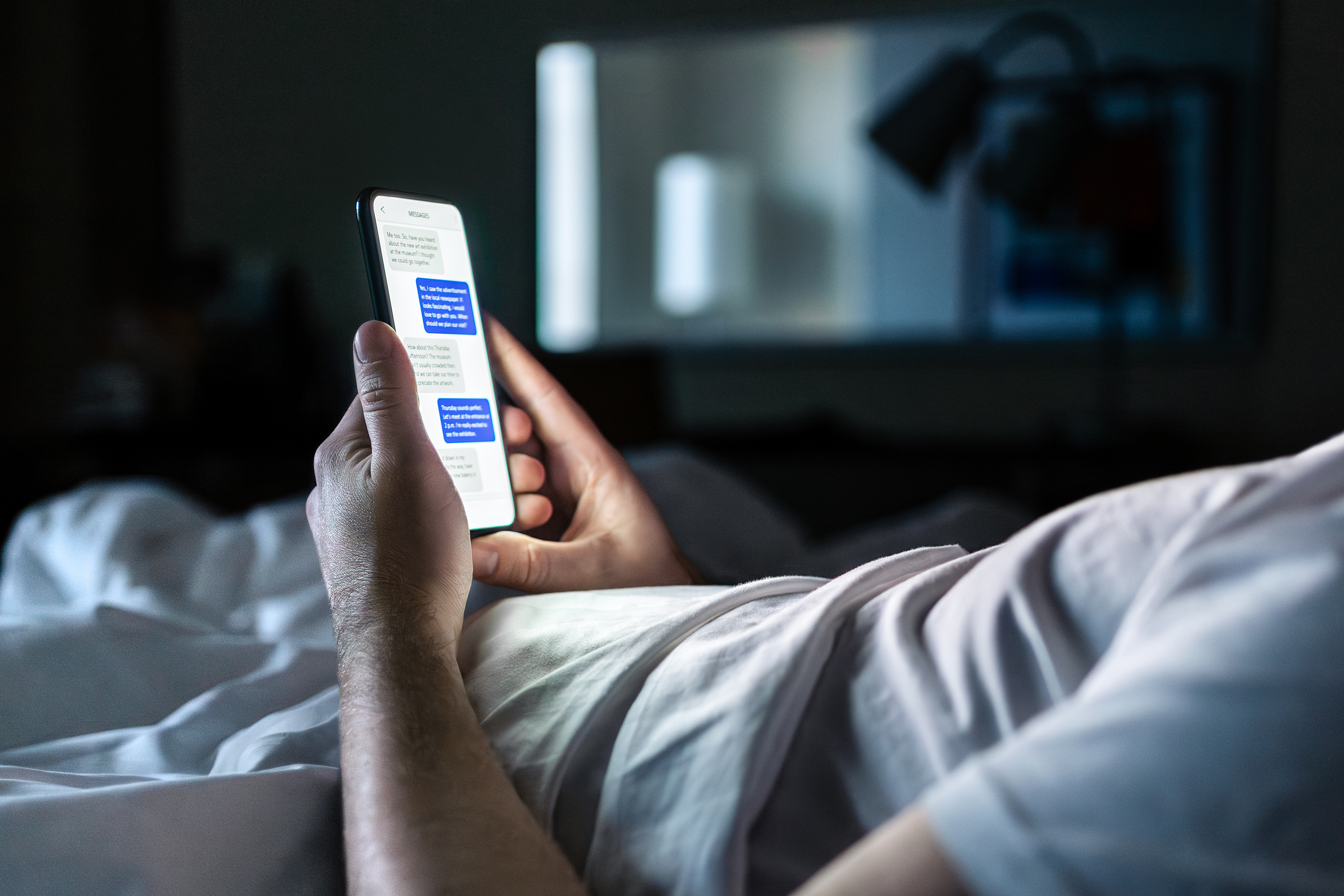 Person lying in bed at night texting on a smartphone symbolizing secrecy and potential infidelity evidence in North Carolina family law