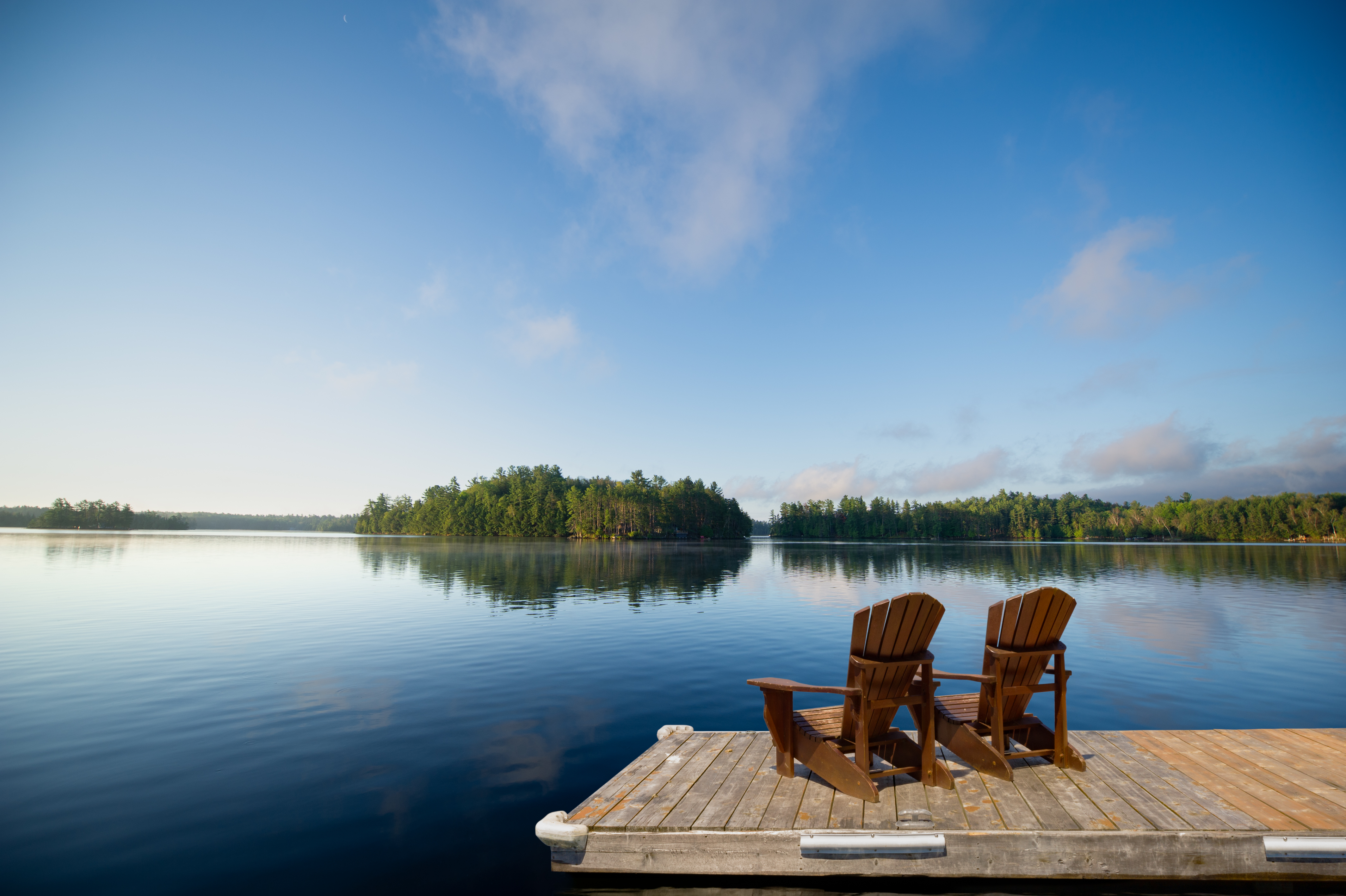 Two wooden chairs sitting on a dock overlooking the calm waters of Lake Norman NC at sunset symbolizing relaxation and Carolina lake life