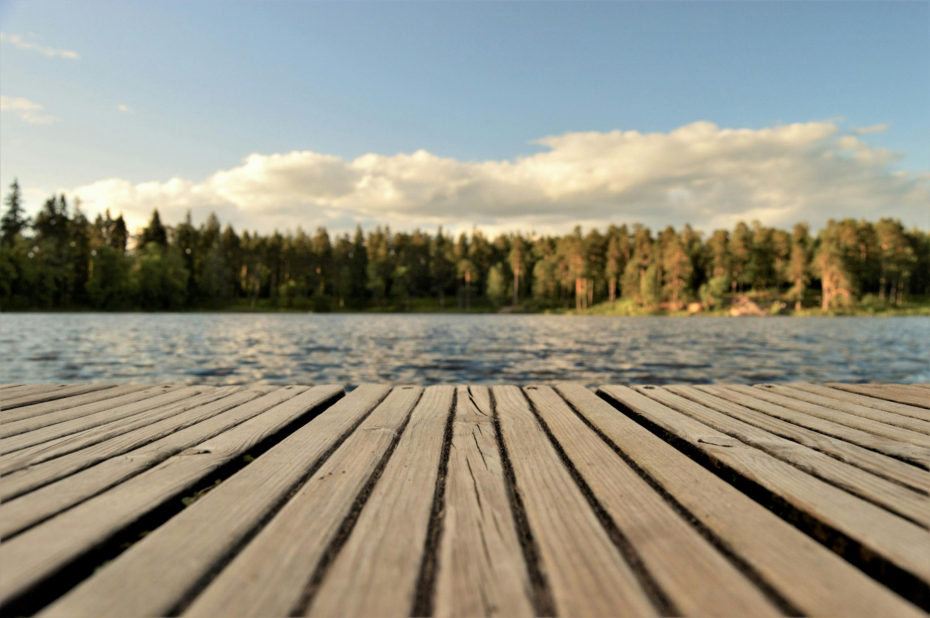 A wooden dock extending into the calm blue waters of Mountain Island Lake in North Carolina surrounded by trees and reflecting the natural beauty of the Lake Norman region