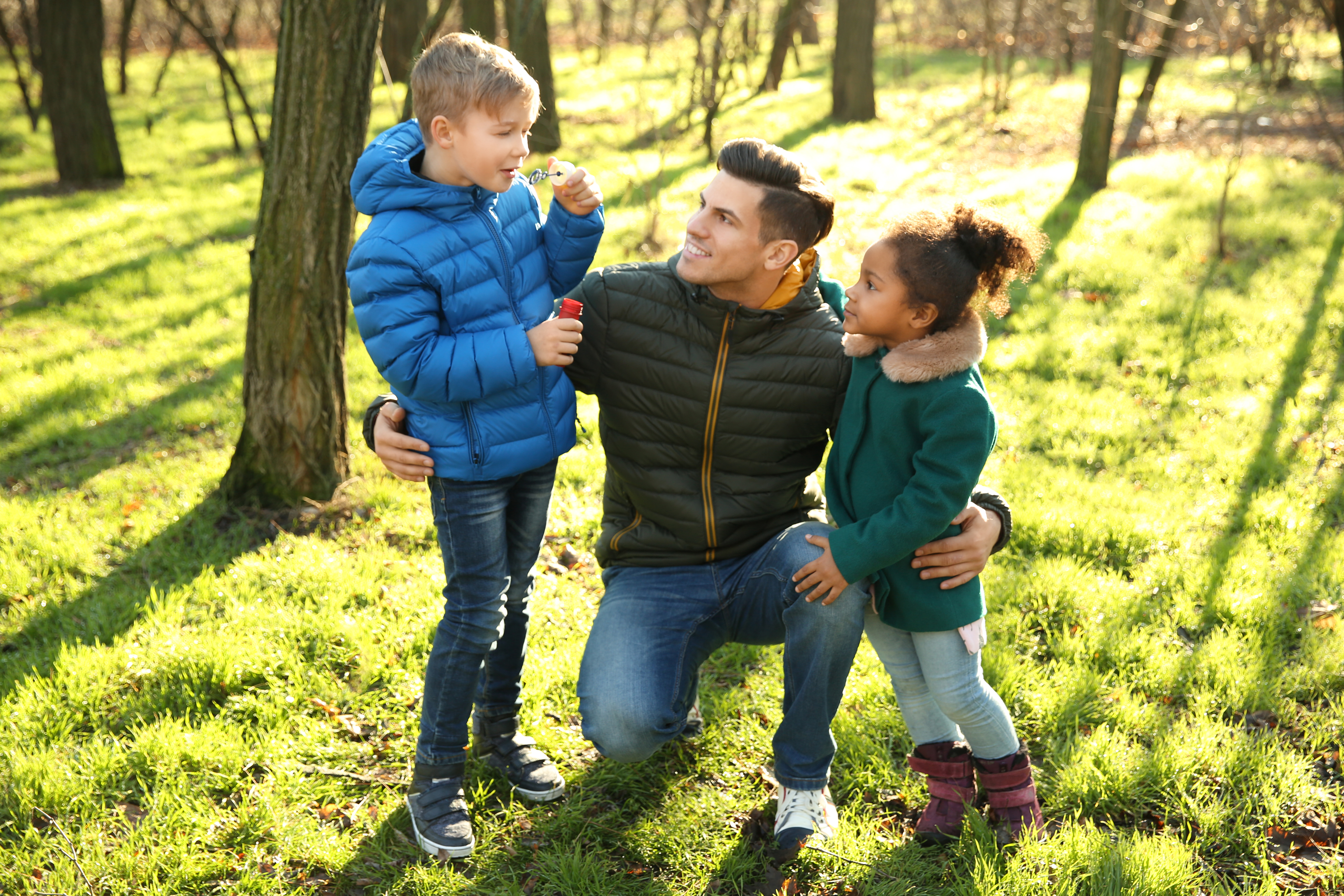 Happy Father with Two Children Custody Case in Huntersville North Carolina LKN Law Smiling father spending time with his two children outdoors in Huntersville North Carolina symbolizing positive co parenting during a custody case